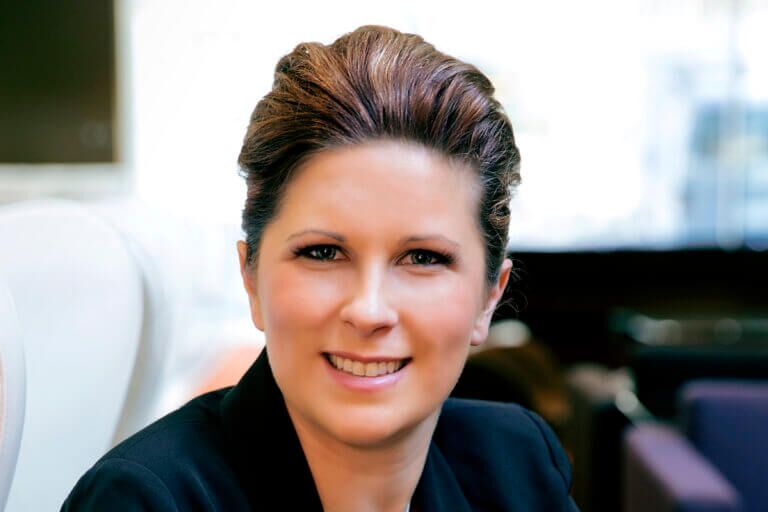 Woman in black jacket smiling facing front