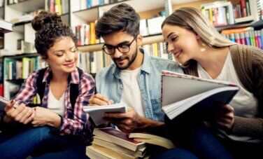 Three people happily discuss something at a library.