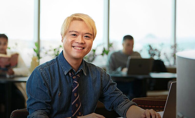 ACAP Psychology Tidus sitting with a laptop at an ACAP University College campus and smiling towards camera (761x761)