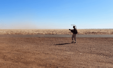 image of desert landscape with a man holding a filming rig in distance right