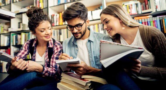 Three people happily discuss something at a library.