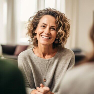 Smiling woman sitting in a therapy session, facing towards camera