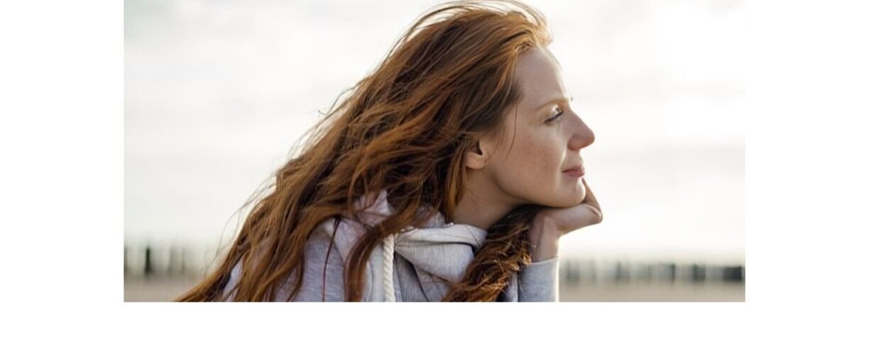Person looking off in distance - hand on chin. Red haired woman