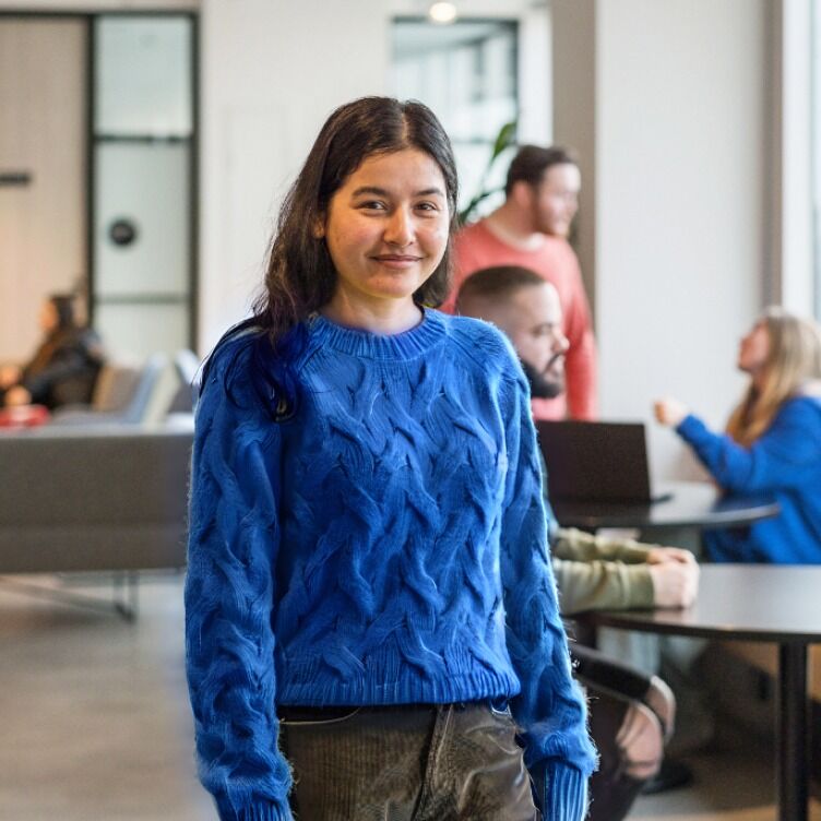 Female applied psychology student standing at an ACAP campus, wearing a blue sweater