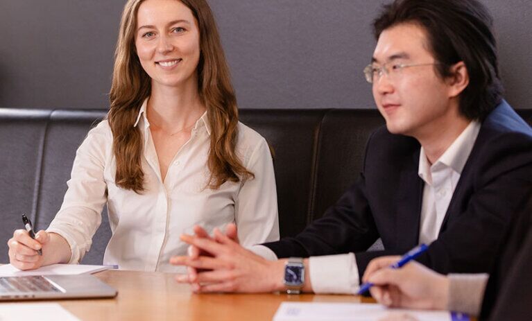 Two Law (PLT) students from ACAP University College in Melbourne sitting at a table in front of notepads and a laptop (828x676)