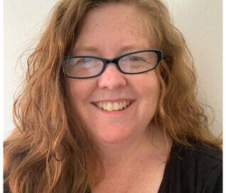 Woman wearing glasses and smiling at the camera