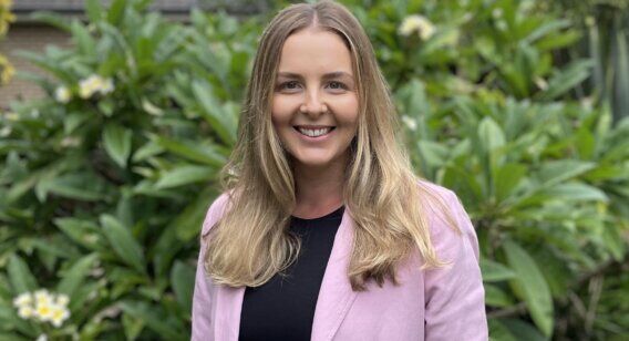 Woman in front of garden in pink jacket