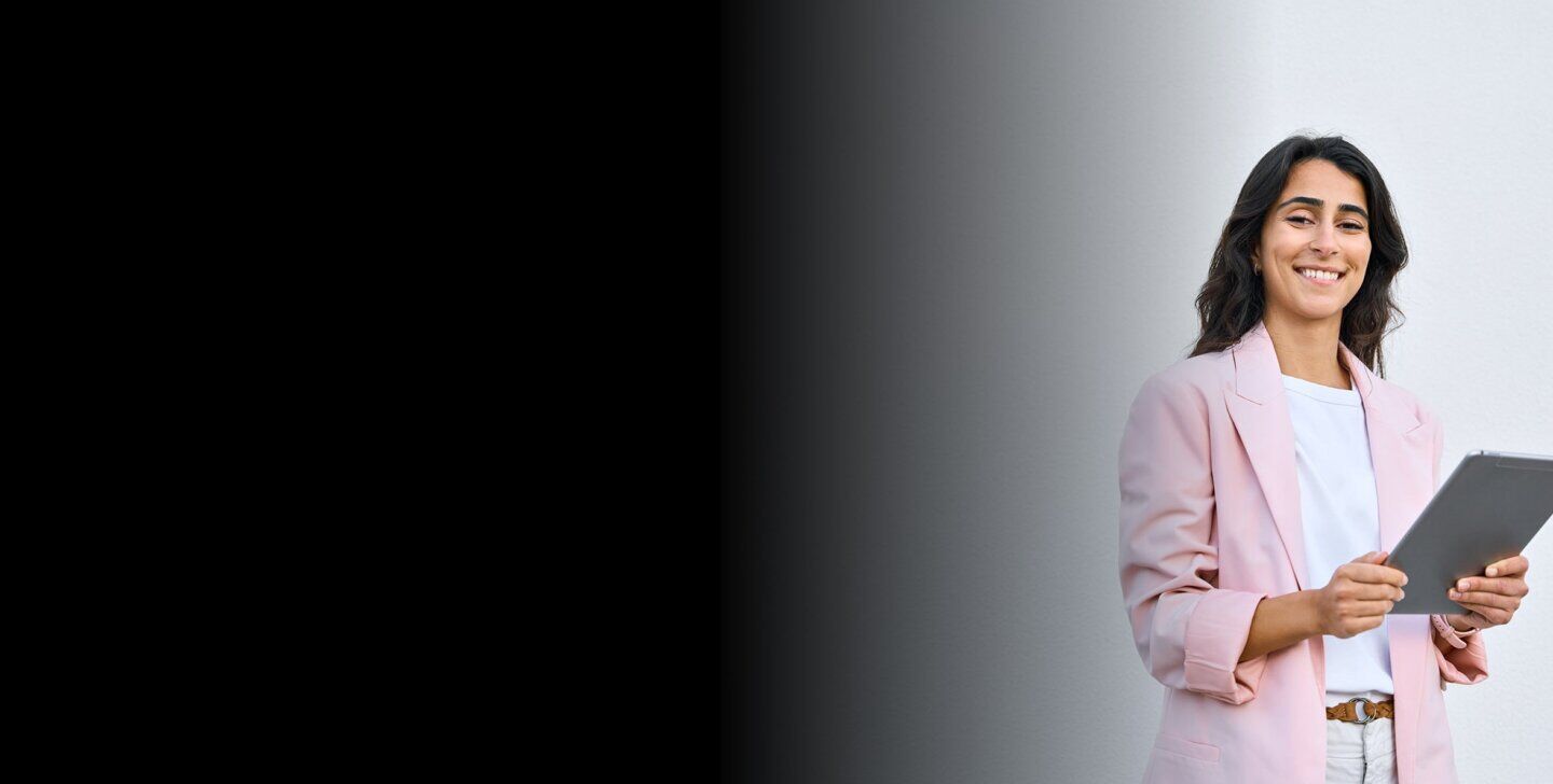 Woman stands in a pink jacket. With device.