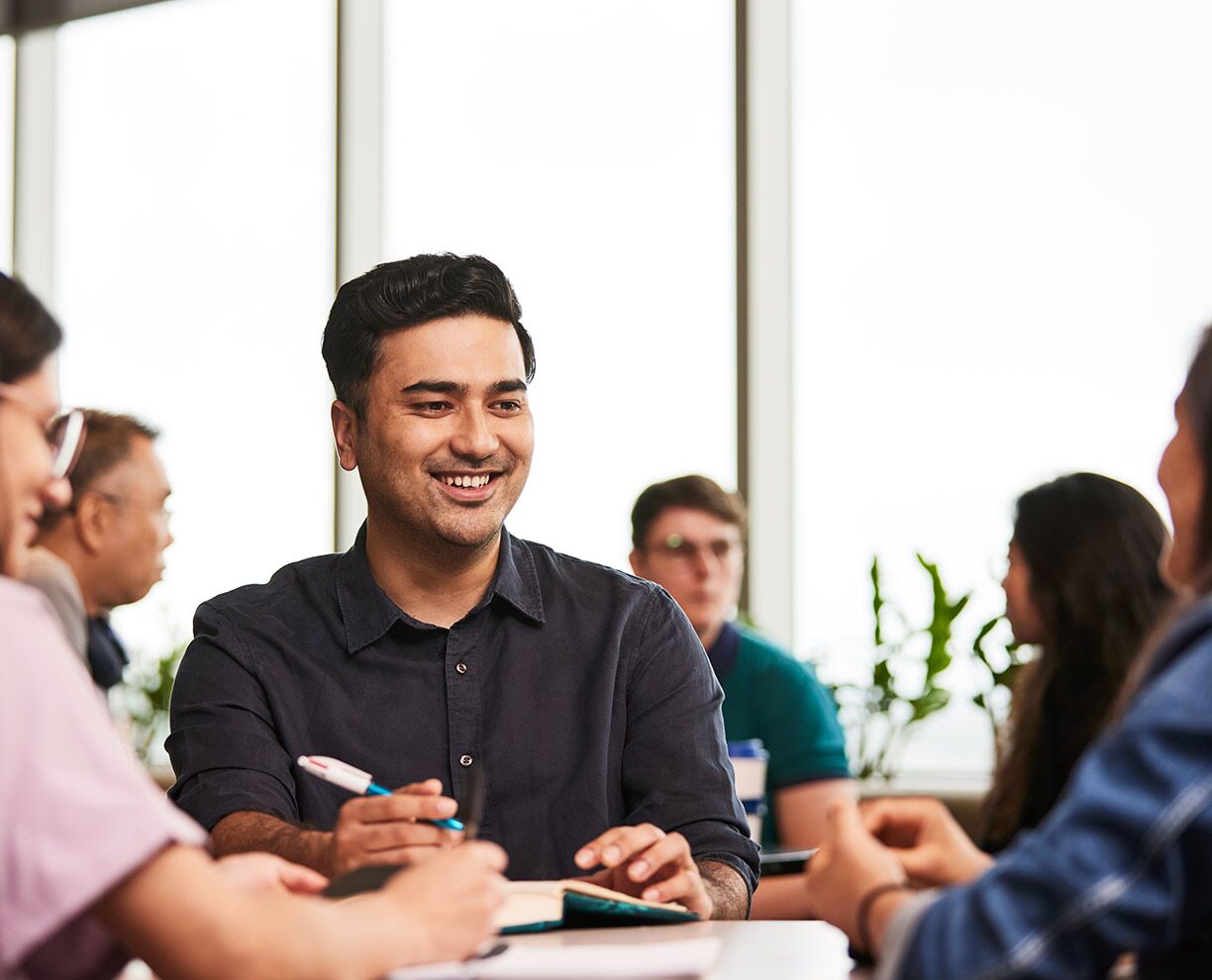 International student Rikesh sitting at a table with two other students at ACAP University College Sydney campus - 1224x990