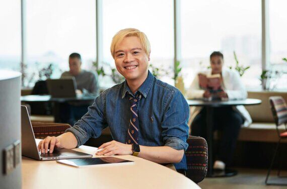 Psychology student Tidus sitting at a desk in front of a laptop at ACAP University College Sydney campus (1140x752)