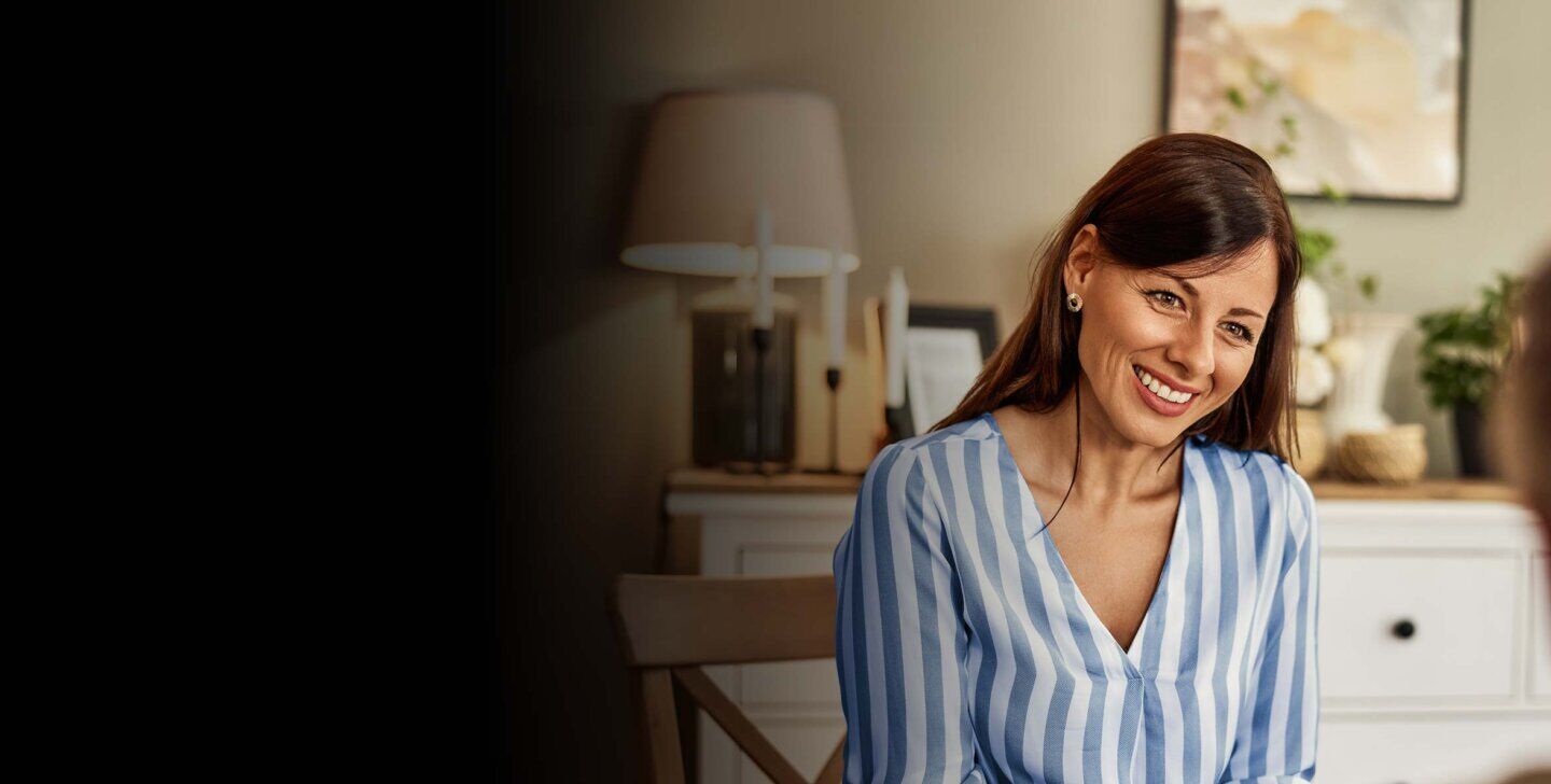 Smiling woman sitting on a chair facing towards camera, sitting across from a client | Bachelor of Counselling